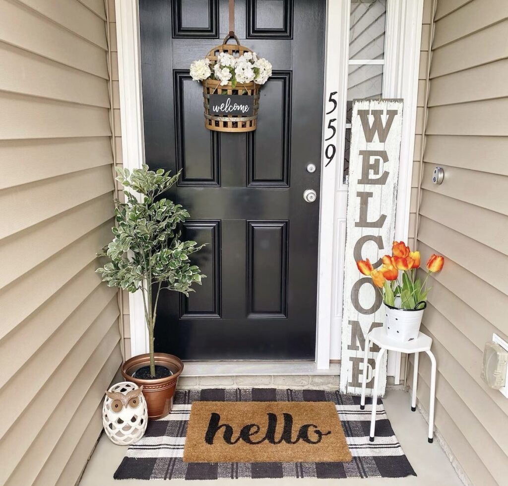 A woven basket with flowers and a welcome sign on a black front door.