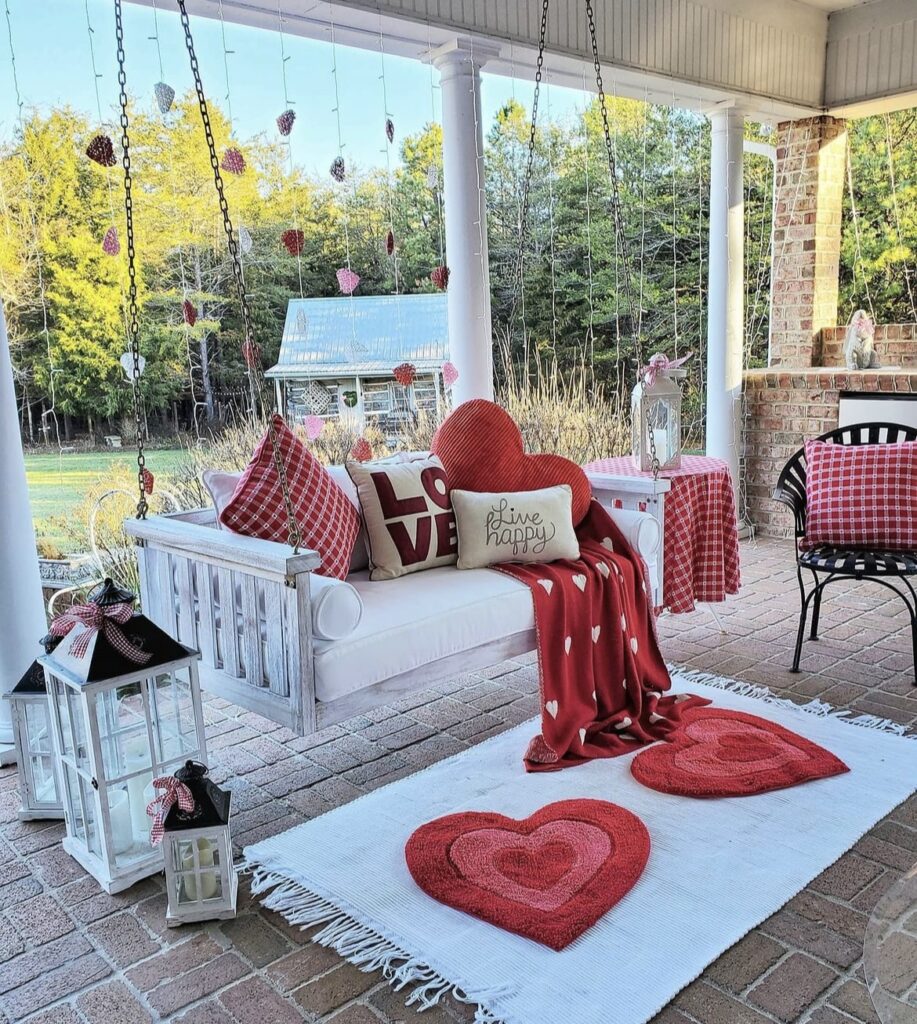 A Valentine front porch with pillows, blanket, rugs, and garlands.