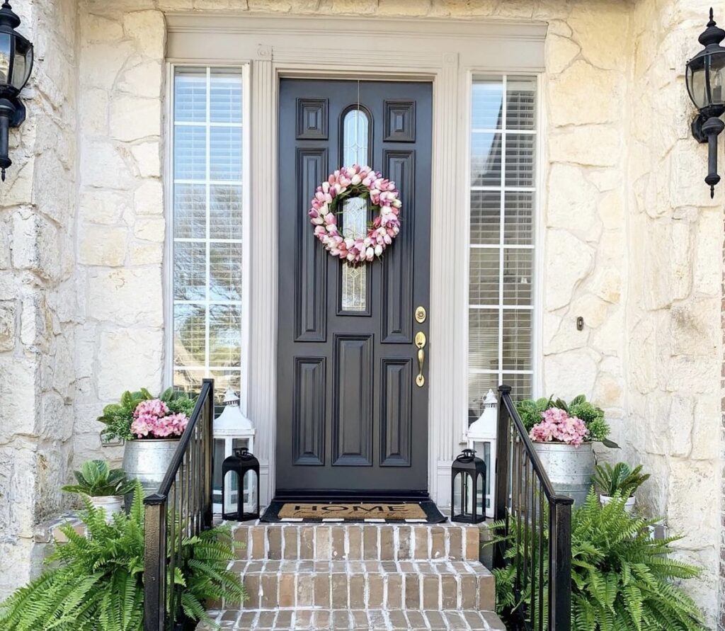 A pink wreath on a black front door.