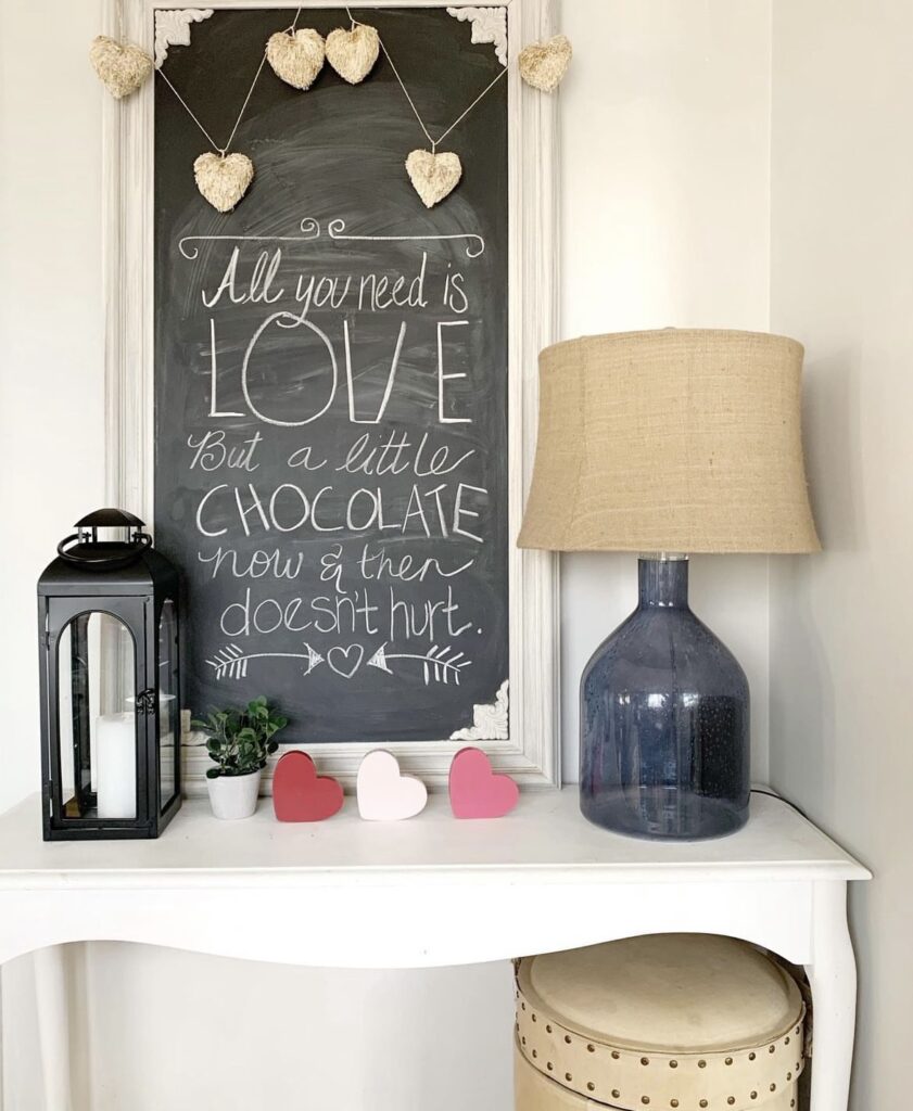 A chalkboard with a love quote, a heart garland, and heart cutouts.