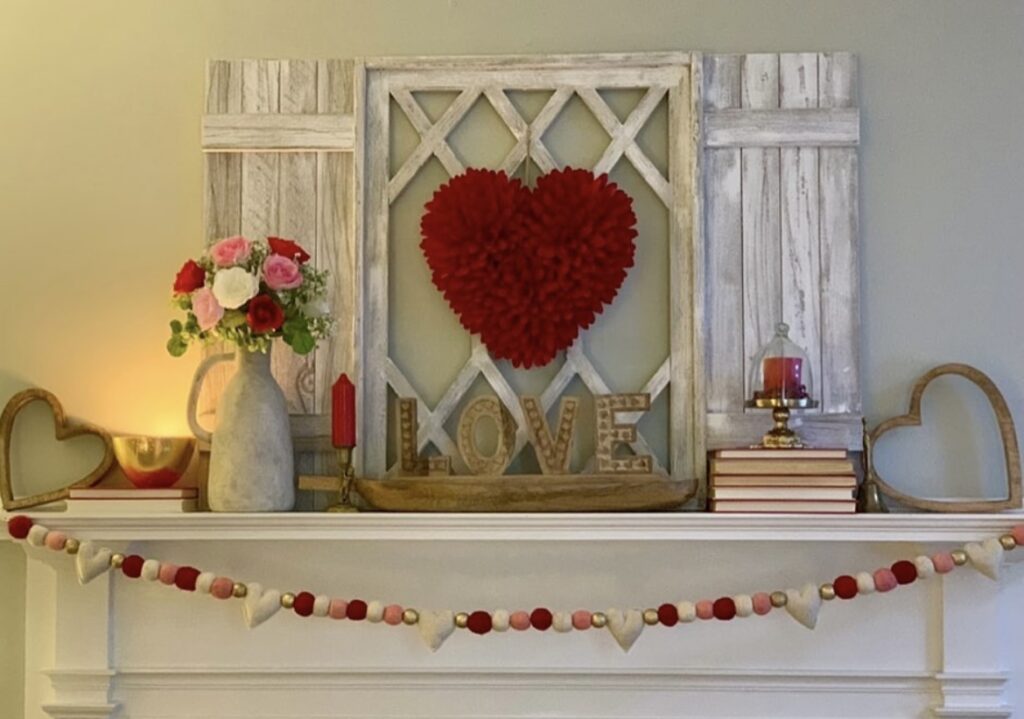 A mantel with a red heart wreath and Valentine garlands.