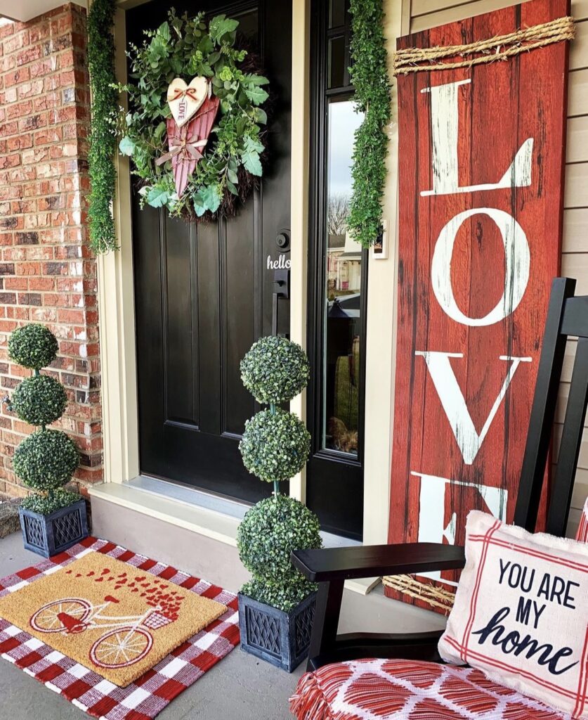 A front porch with a love sign and Valentine pillow.