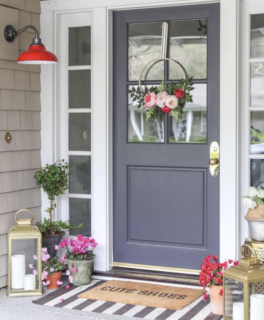 A front porch with a floral wreath and candle lanterns.