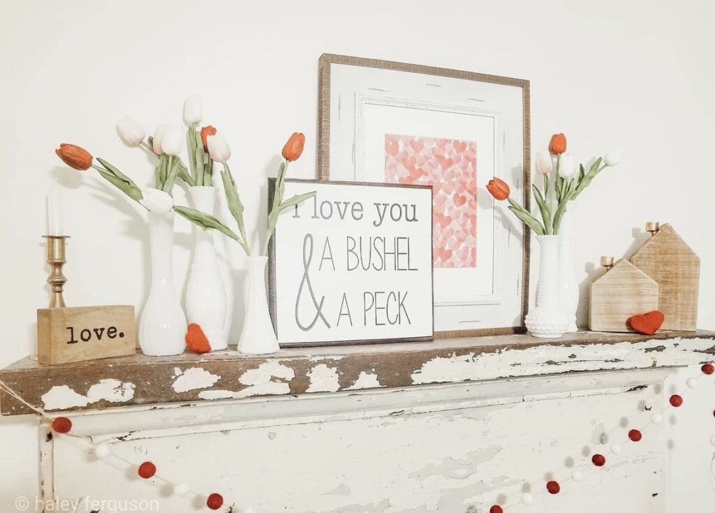 A mantel with Valentine quotes and flowers.