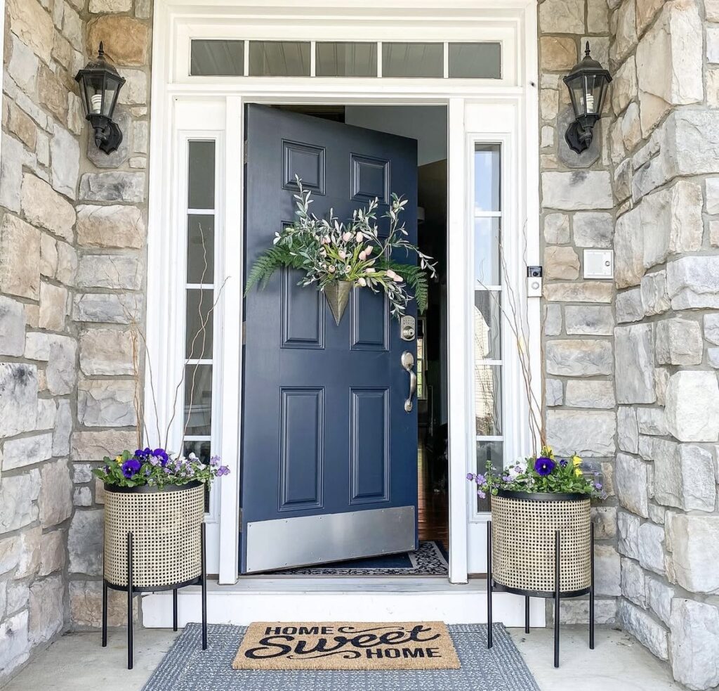 A gold basket filled with plants on a black front door.