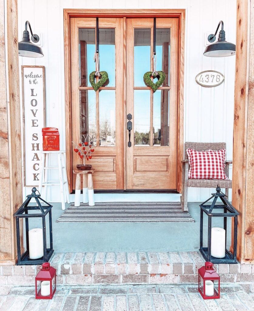 A front porch with an heart-shaped wreath and candle lanterns.