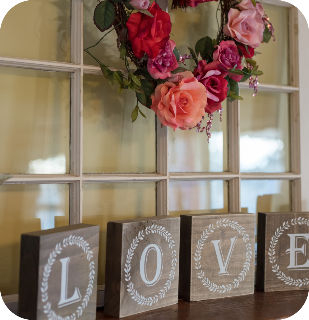 A mantel with a love sign and a floral wreath.