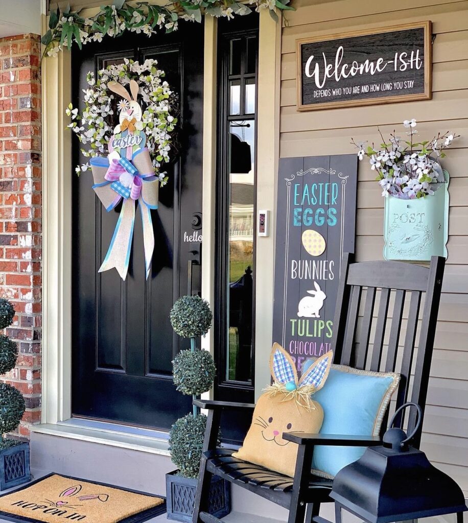 An Easter wreath on a black front door and an easter sign on a front porch.