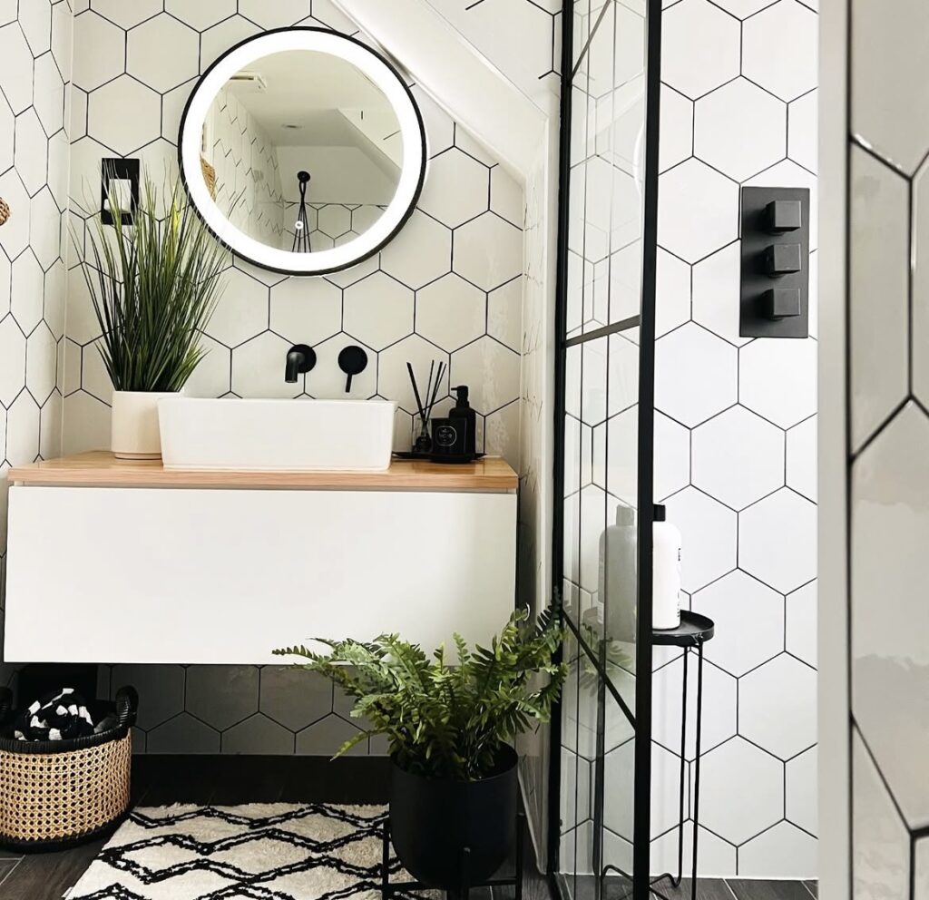 A modern bathroom with black and white patterned tiles and a rug.