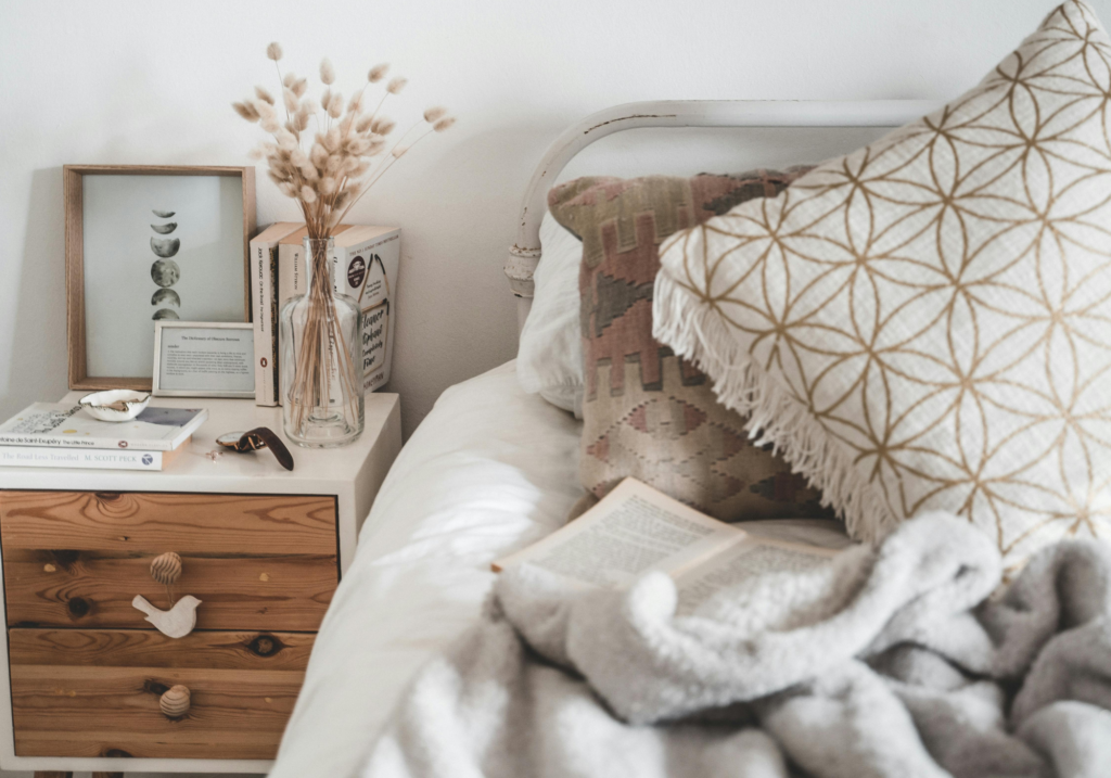 A neutral bed with a wooden nightstand.