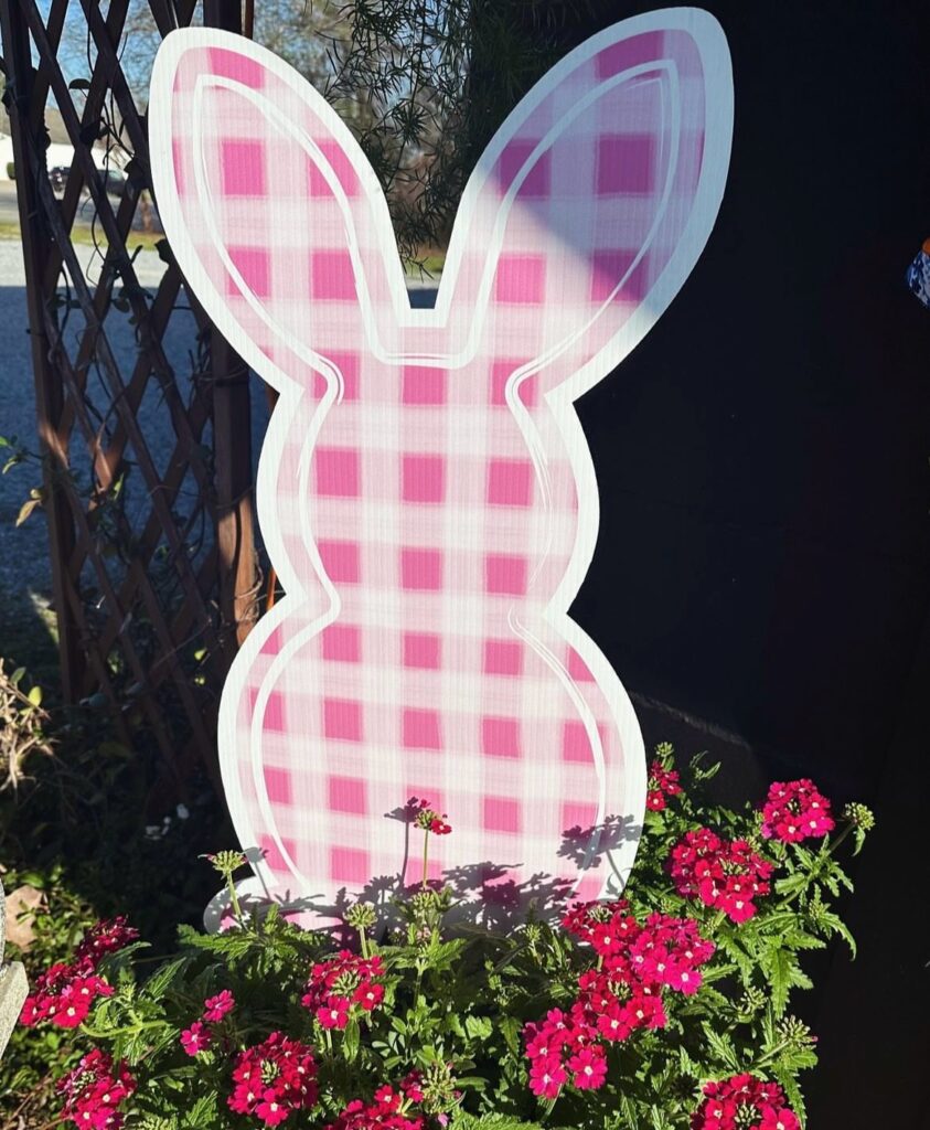 A pink and white rabbit cutout in a planter.