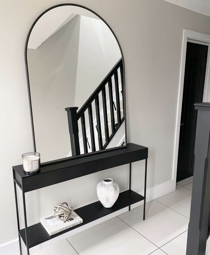 An arched mirror in an entryway.