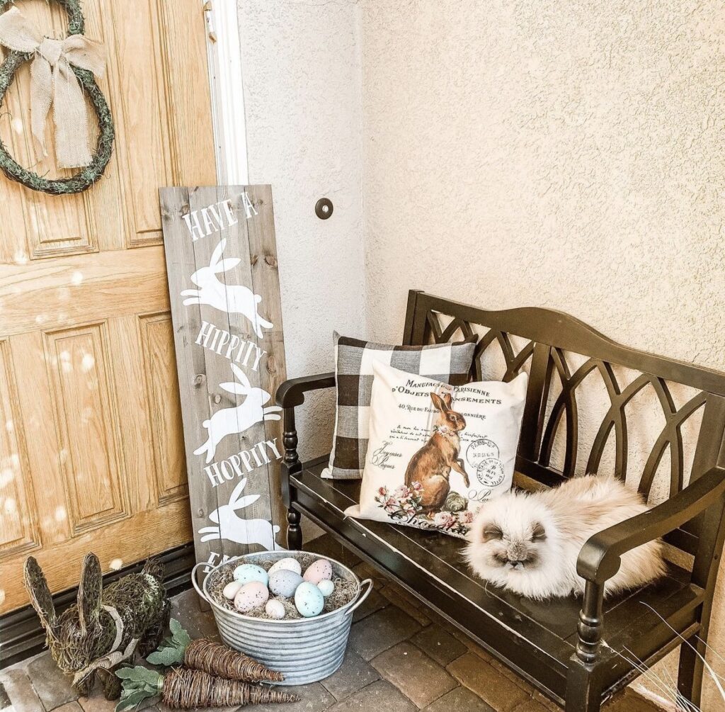 Easter pillows on a black bench on a front porch.