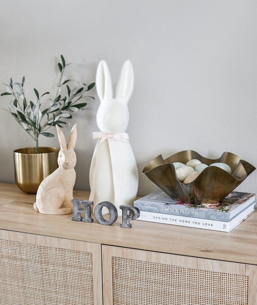 Rabbit figurines with a hop sign and Easter eggs in a gold bowl.