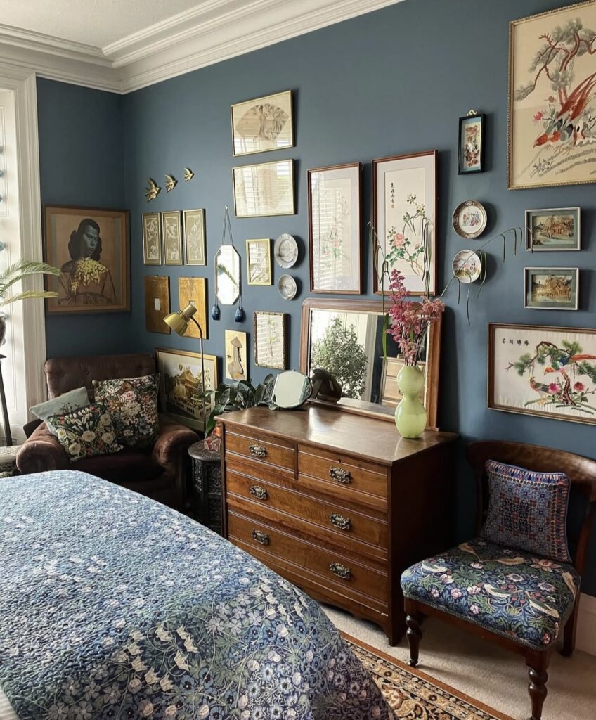 A bedroom with a gallery wall on a blue wall.