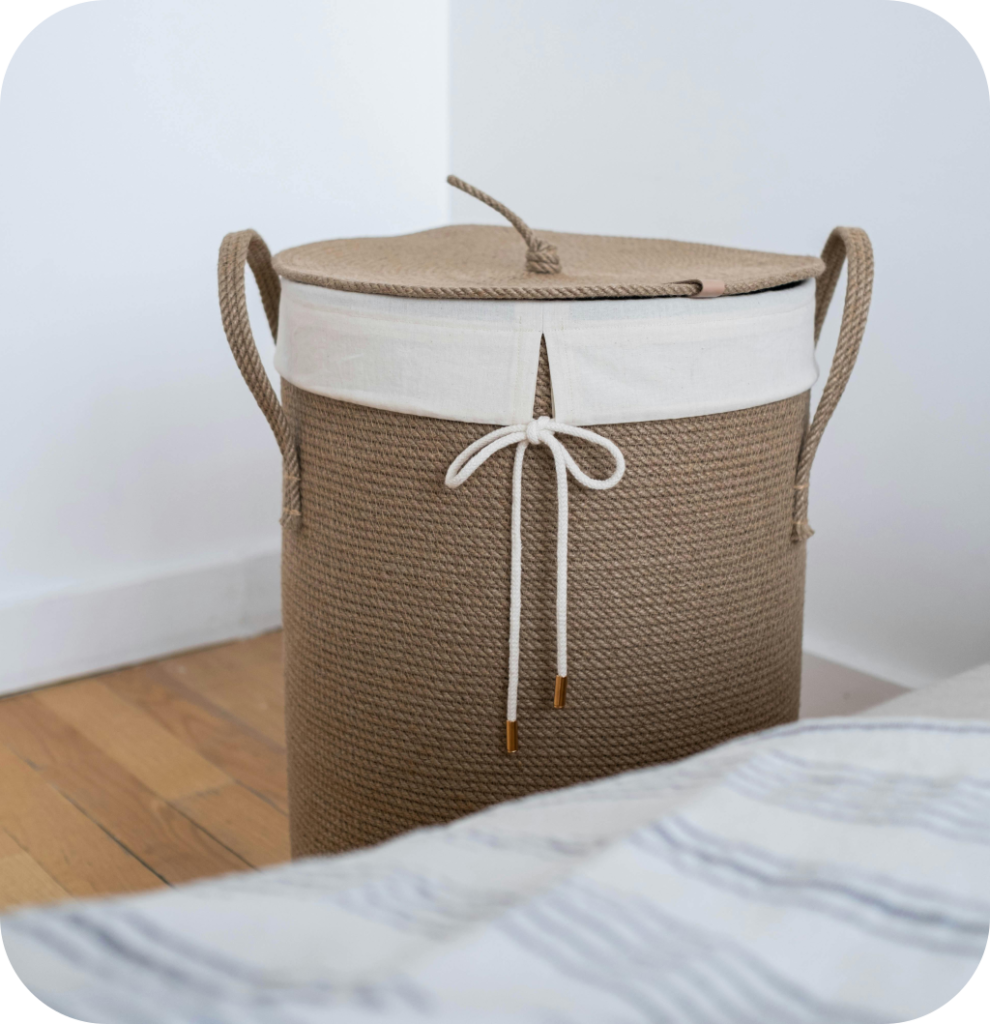 A woven basket next to a bed with blankets in it.