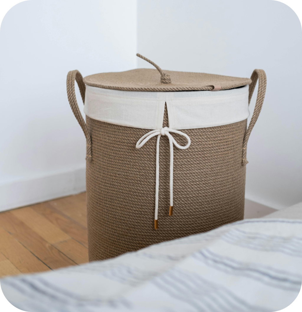 A woven basket next to a bed with blankets in it.