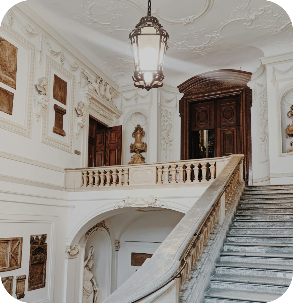 A castle entryway with intricate staircase and molding.