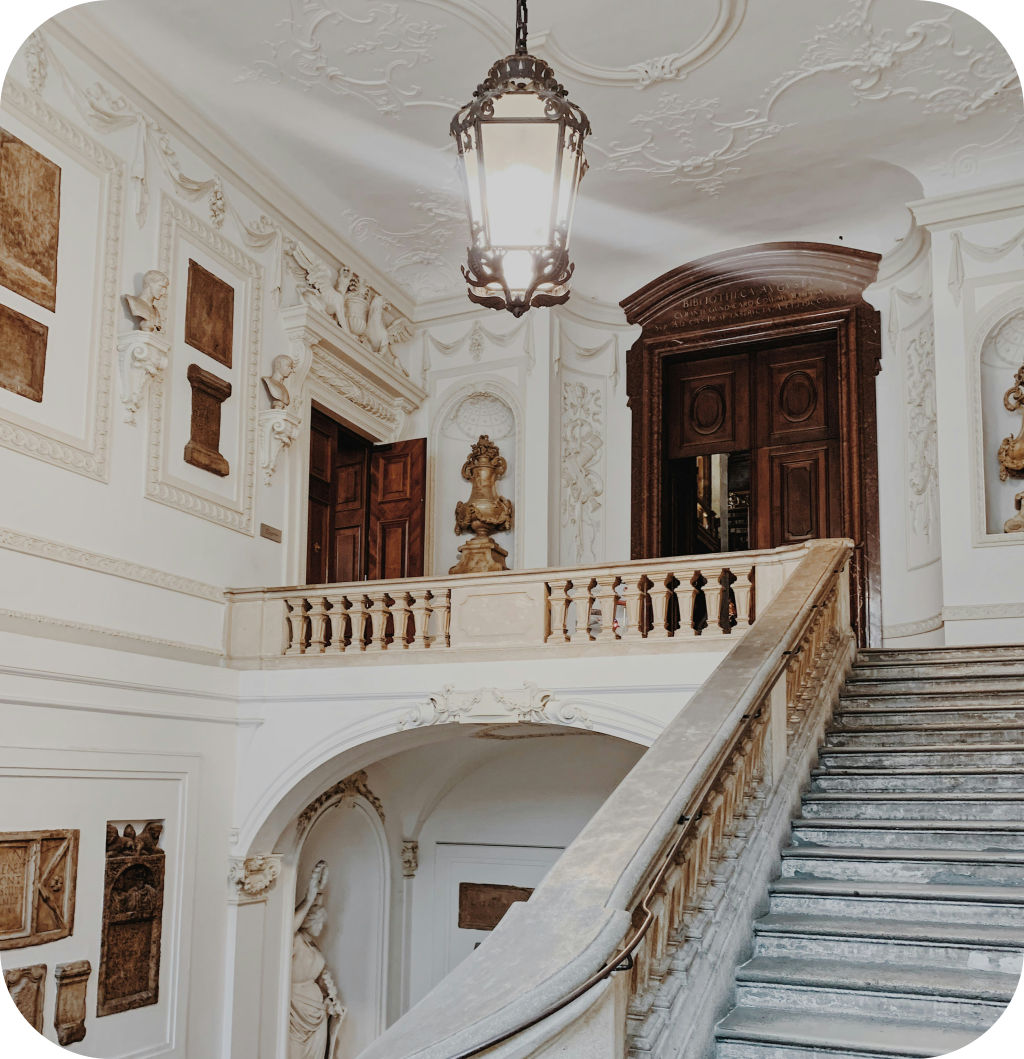 A castle entryway with intricate staircase and molding.