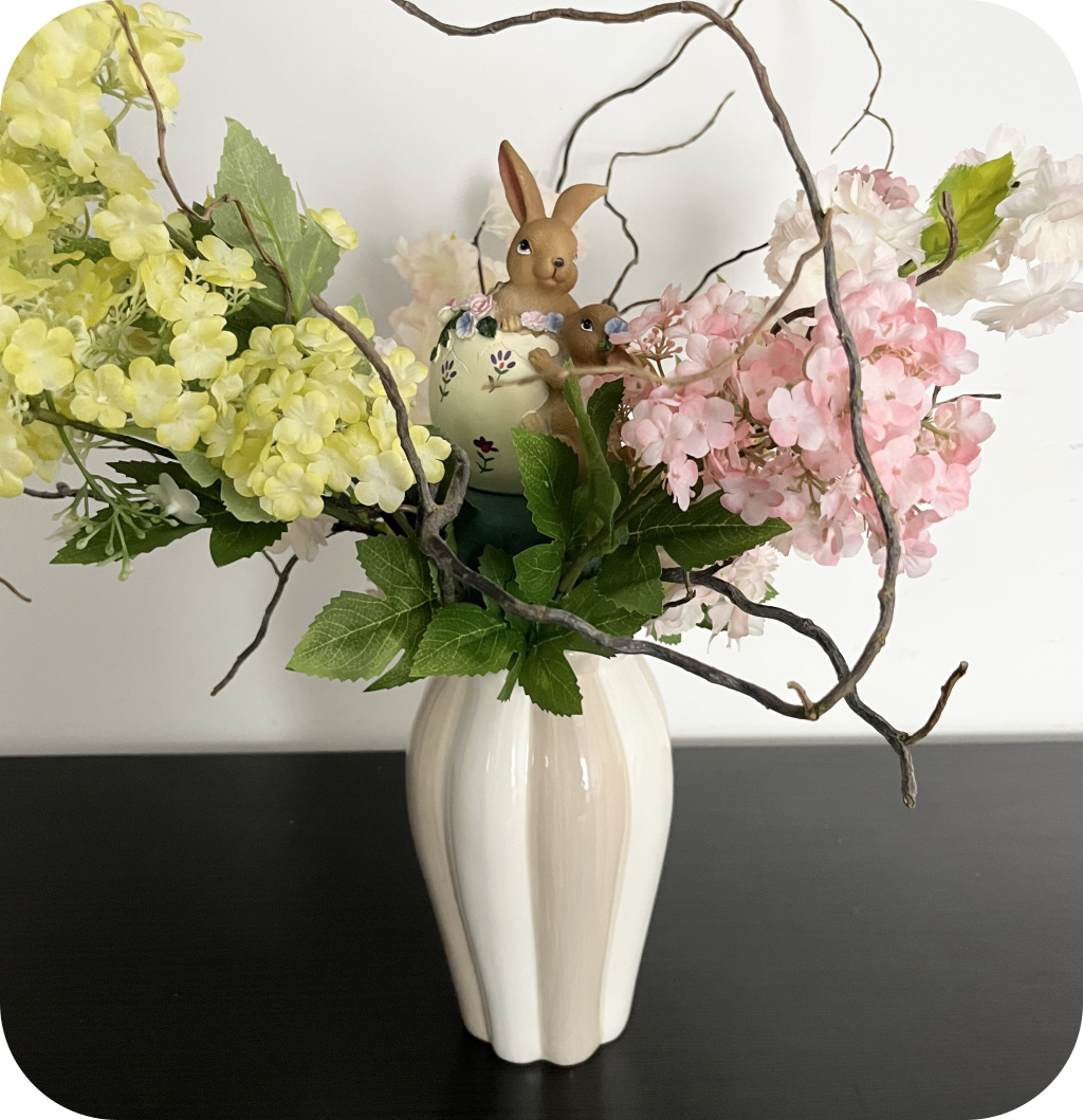 A minimalist vase with pink and yellow flowers, curly branches, and a bunny figurine. ©ASTRAPEARL - DO NOT USE