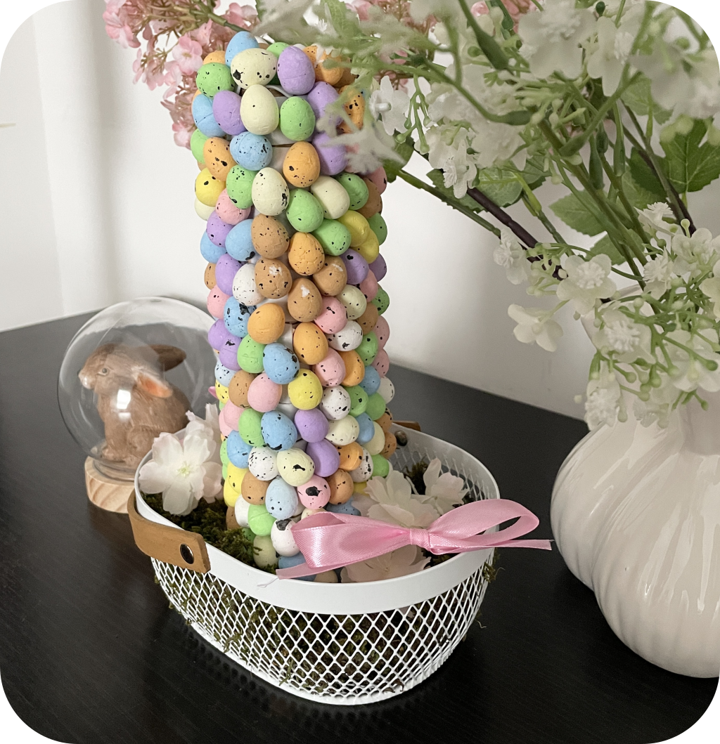 Carboard cone with Easter eggs in a basket filled with moss, fake flowers, and ribbon bows. ©ASTRAPEARL - DO NOT USE