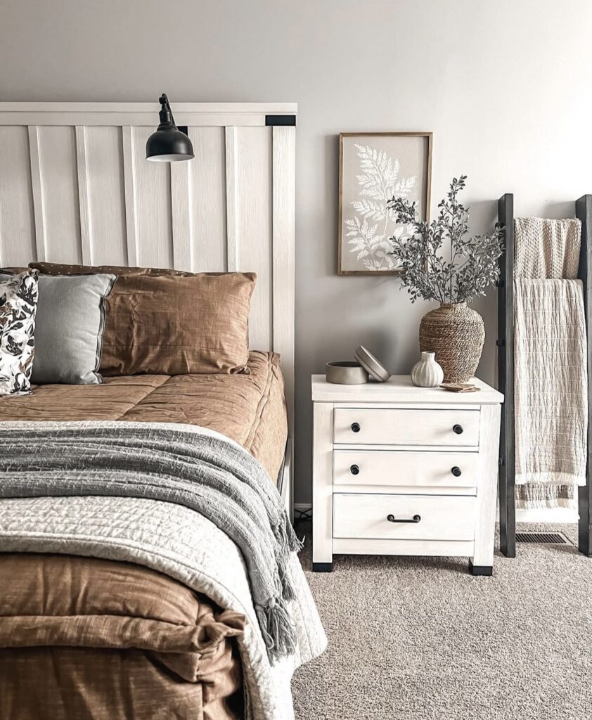 A white nightstand with a woven lamp and a minimalist print.