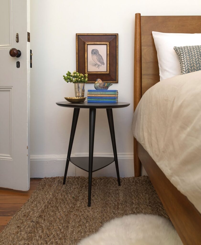 A black nightstand with a bird figurine.