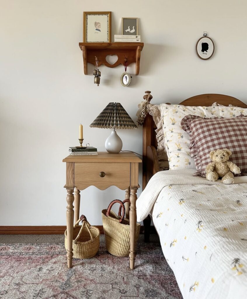 A vintage bedroom with a wooden nightstand, a bronze candlestick holder, and a brown patterned lamp.