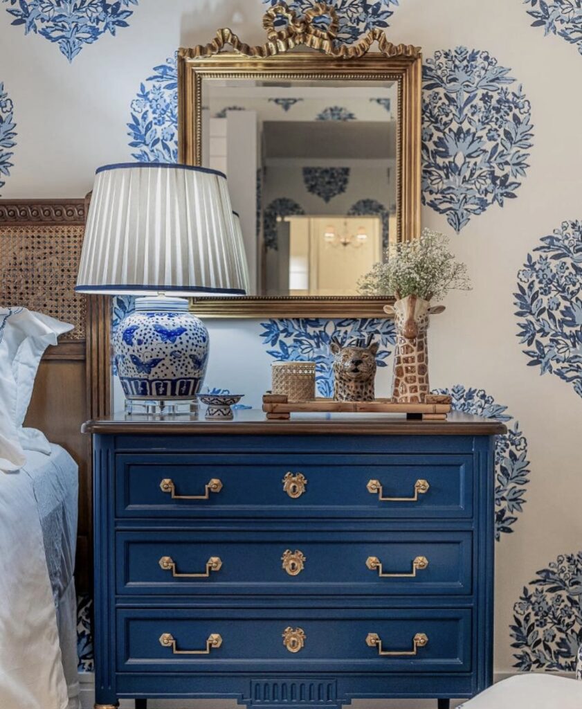 A vintage and elegant bedroom with an antique blue nightstand and animal figurines.