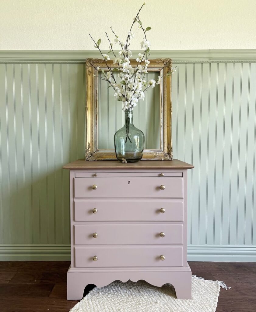 A pink nightstand with an antique frame.