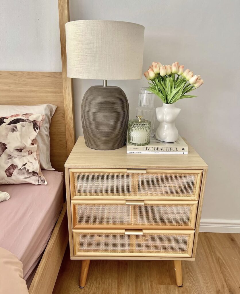 A cane nightstand with a body vase and a brown lamp.