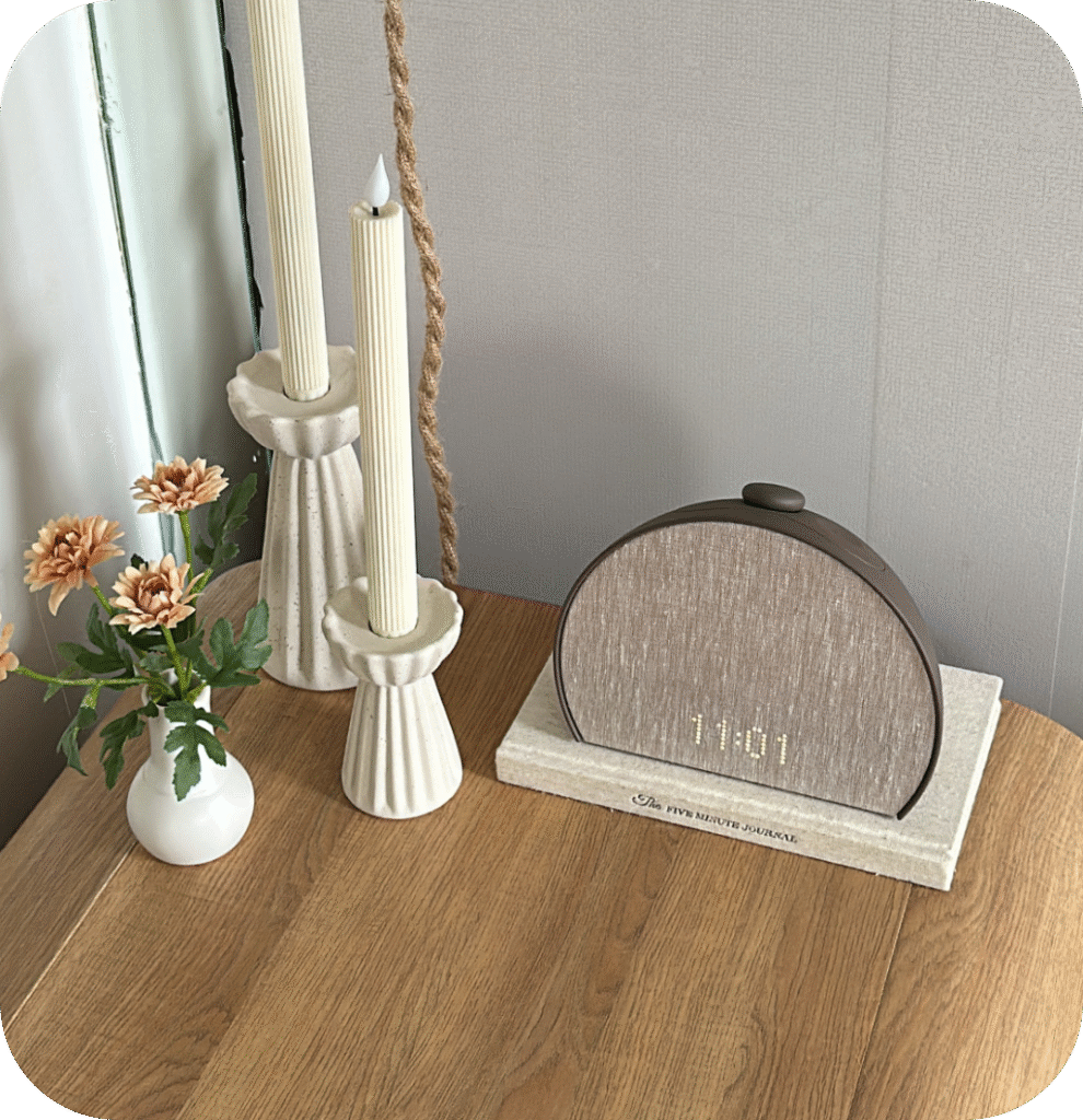 A curved nightstand with candles and flowers.