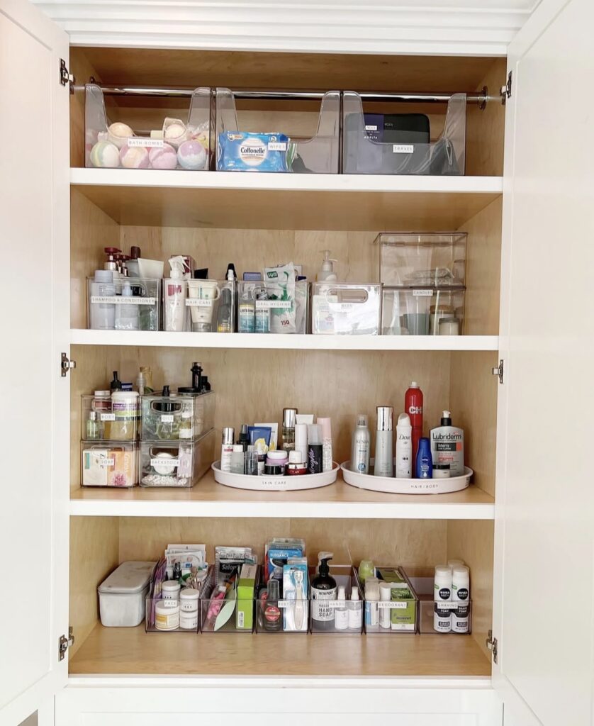 A cabinet with clear bins filled with bathroom products.
