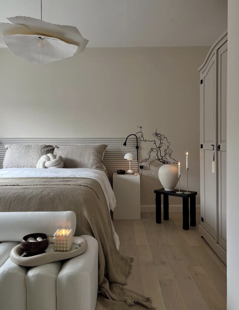 A modern bedroom with a geometric vase and candle.