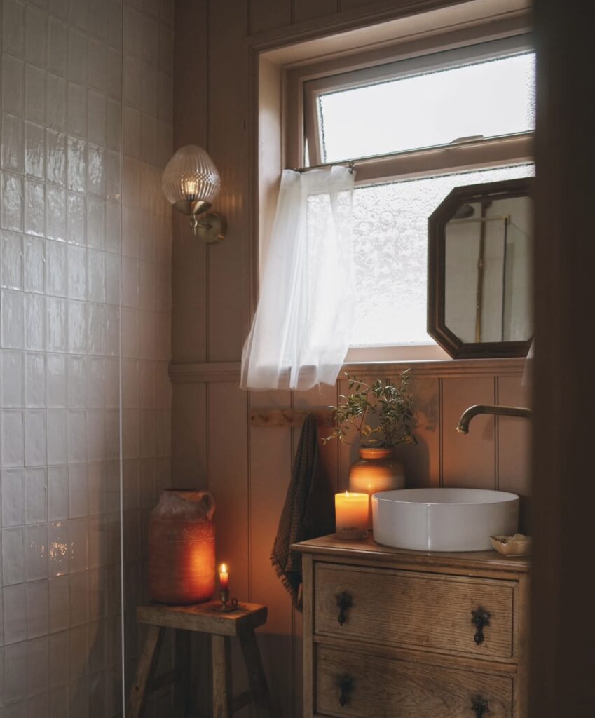 A cozy bathroom with a stool and a candle.