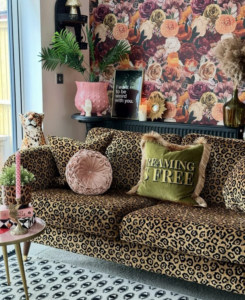 A living room with a leopard print sofa and floral wallpaper.