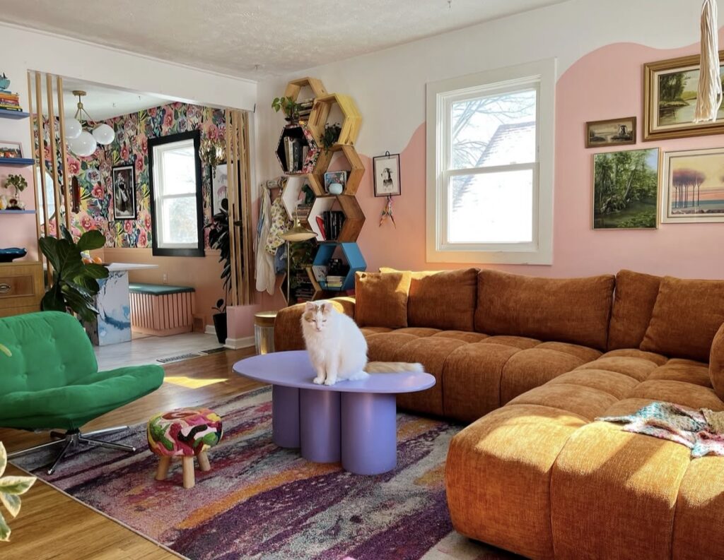A living room with an orange sofa and pink walls.