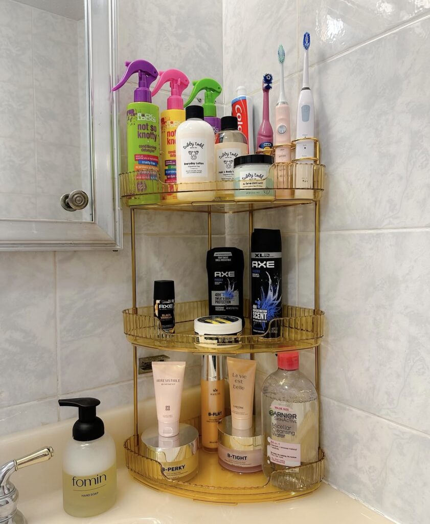 A gold 3-tier corner organizer filled with bathroom products.