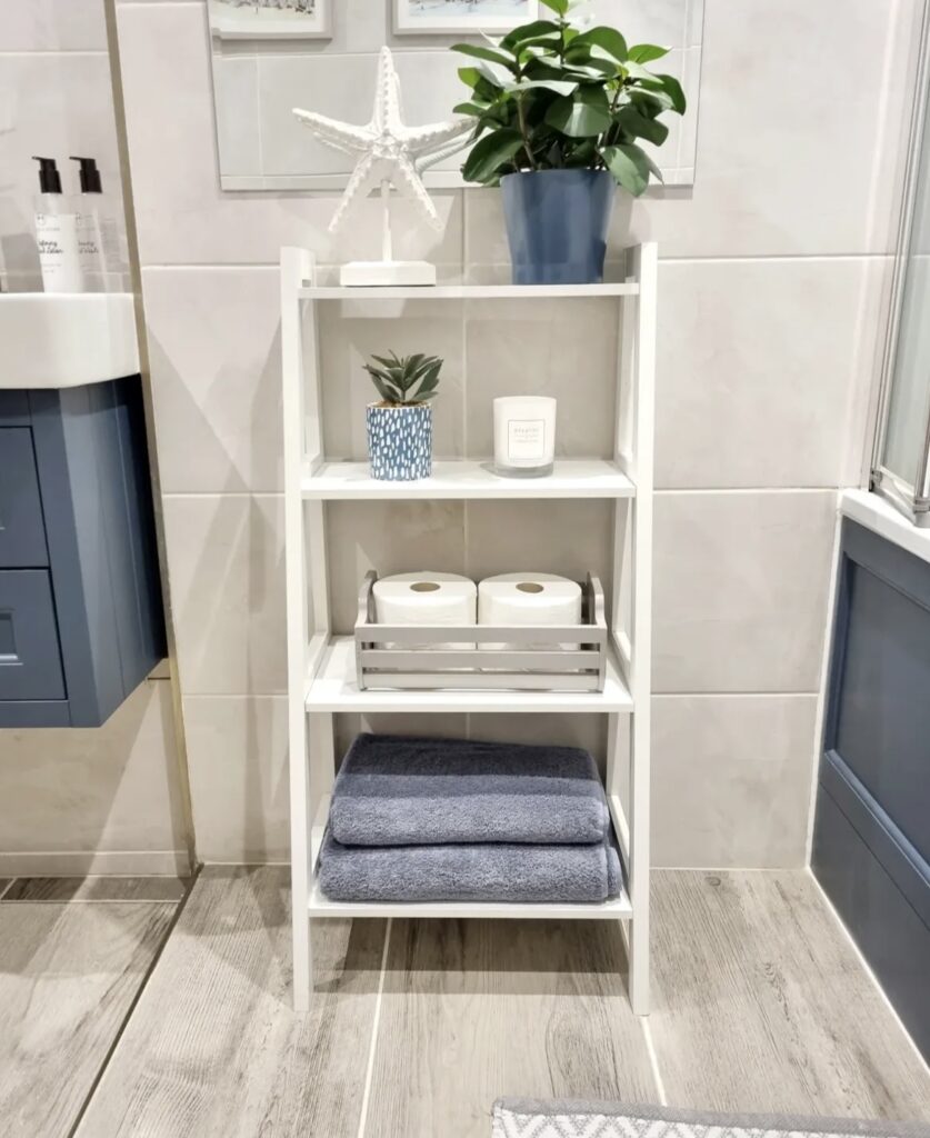 A white ladder shelf with towels and toilet paper.