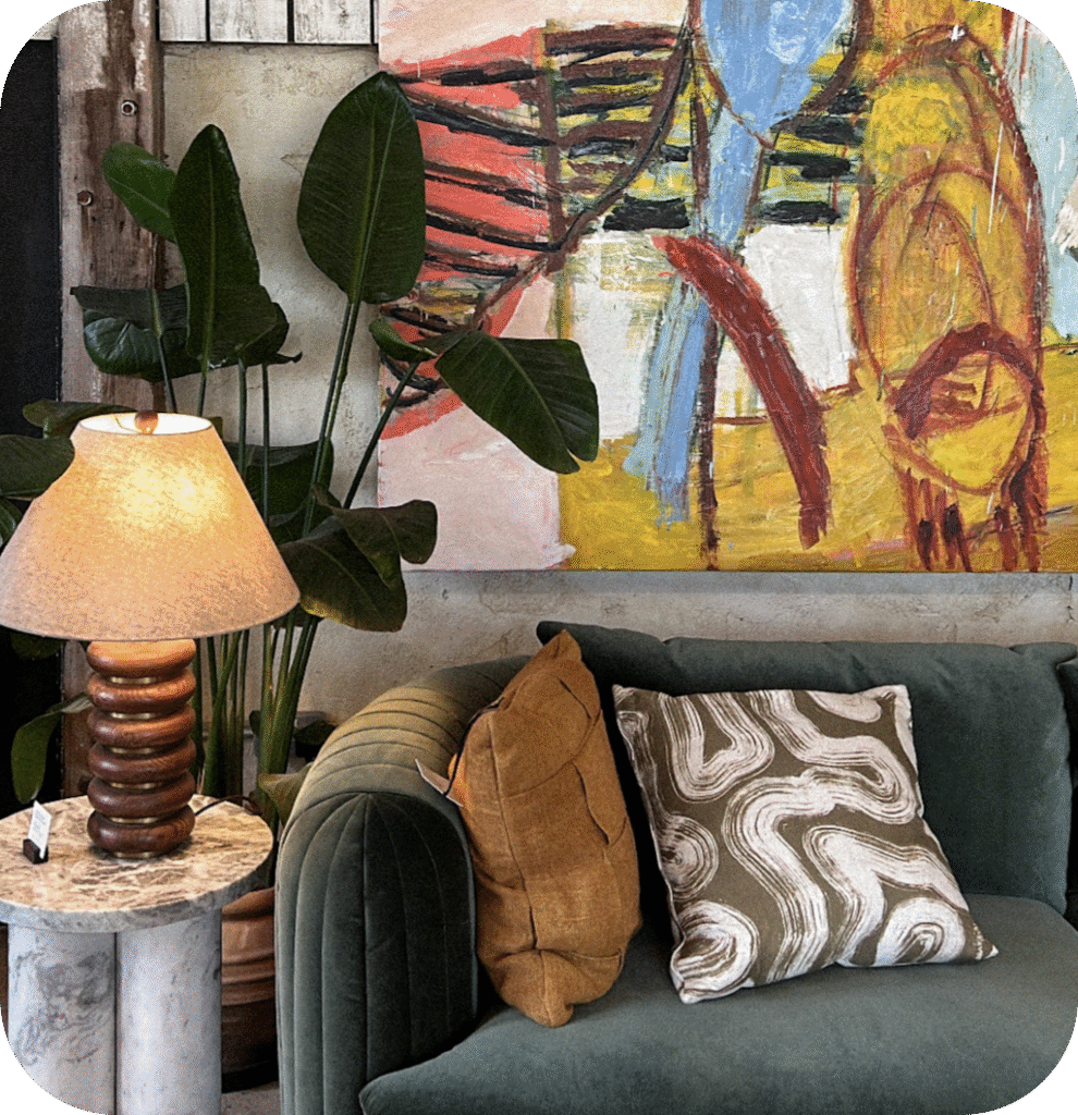 A gray sofa with patterned pillows, an abstract painting and a cool lamp.
