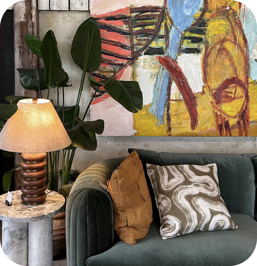 A gray sofa with patterned pillows, an abstract painting and a cool lamp.