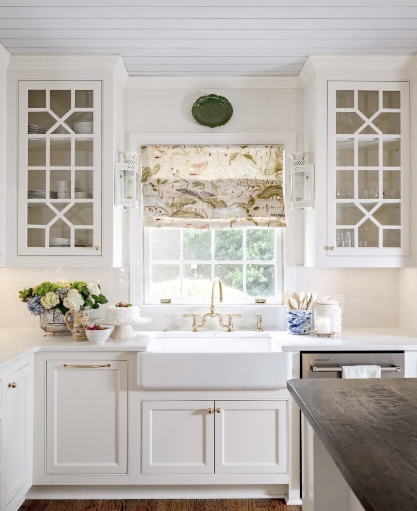 A white kitchen cabinet with duck curtains.