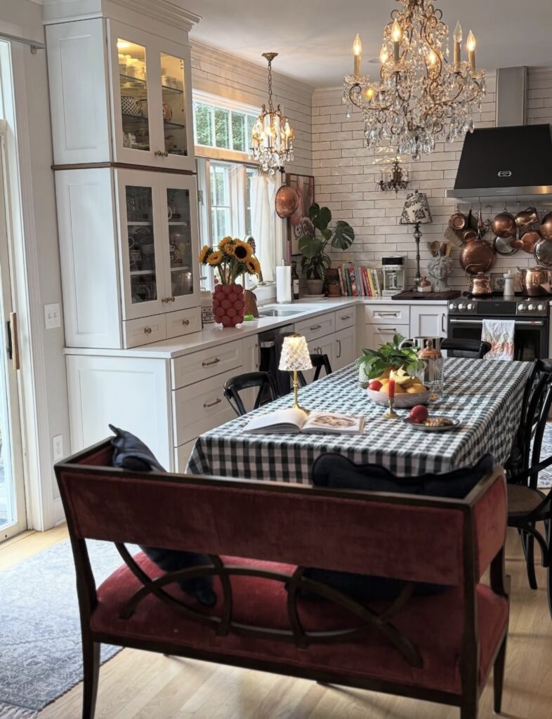 A white kitchen cabinet with bronze pots.