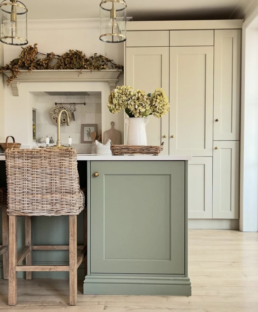 A white kitchen cabinet with dried flowers above it.