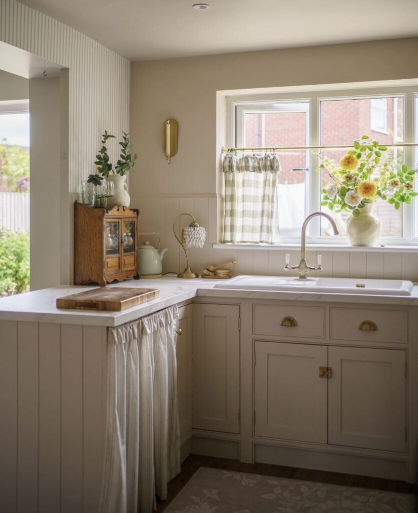 A white kitchen cabinet with cabinet curtains.