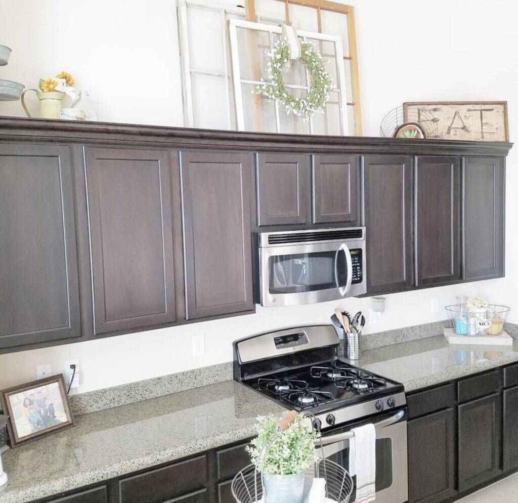 A dark brown kitchen cabinet with farmhouse deccorations above it.