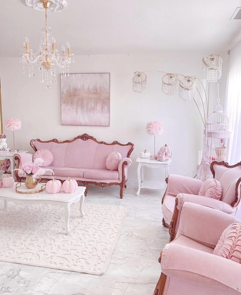 An antique white living room with pink antique sofa and chairs and pink pumpkins.