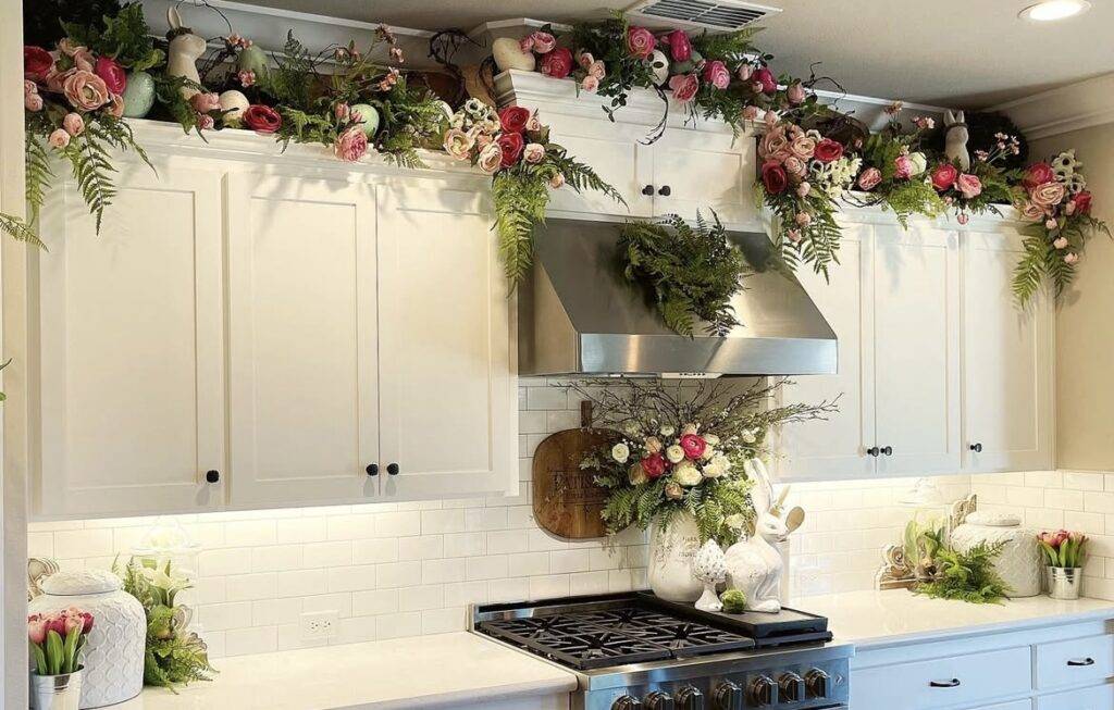 A white kitchen cabinet with spring decorations above it.