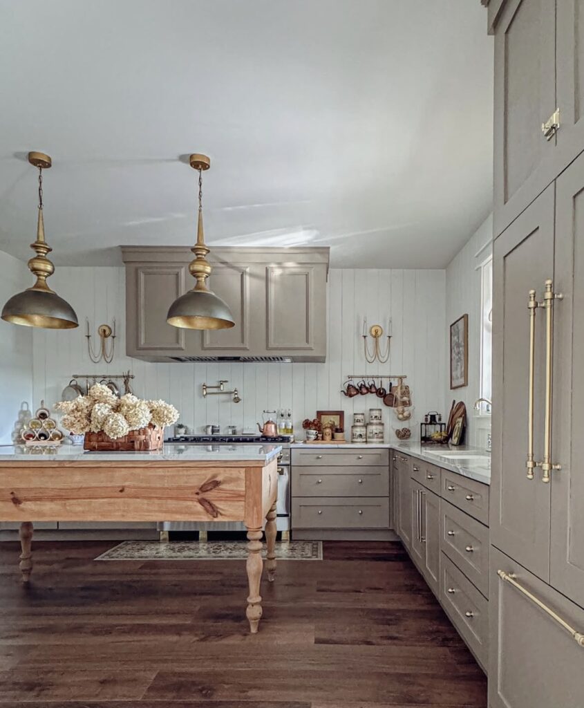A gray kitchen cabinet with an antique table as a kitchen island.