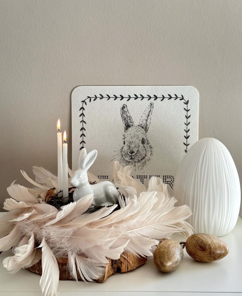 A bird nest made of feathers with a white bunny figurine.